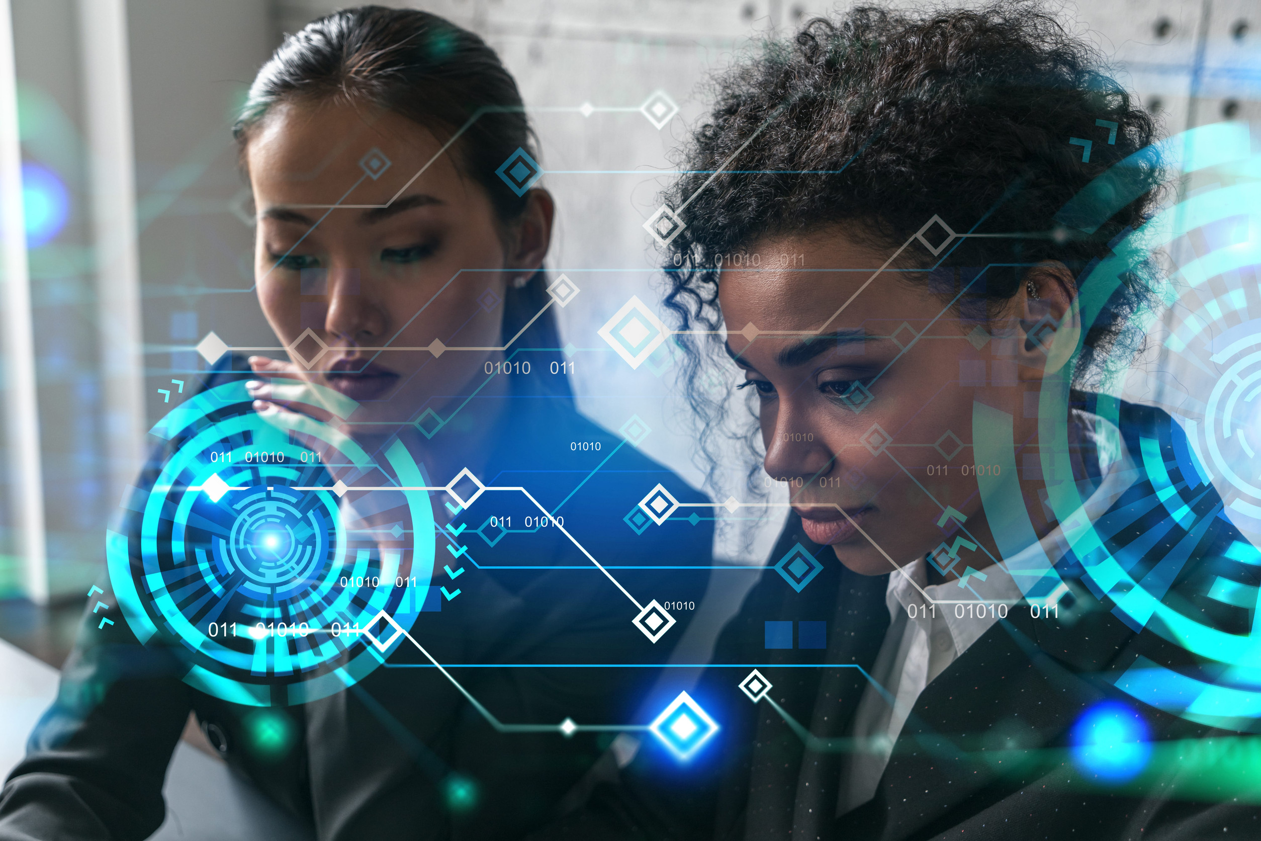 Two businesswomen reviewing a technology plan with a digital data overlay