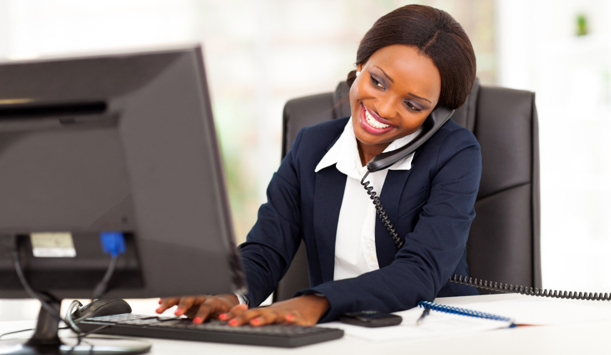 A woman working on a computer while talking on the phone