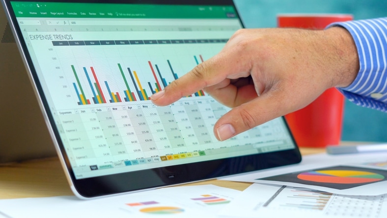 Businessman pointing and expanding graphs on modern touch screen technology laptop close up.