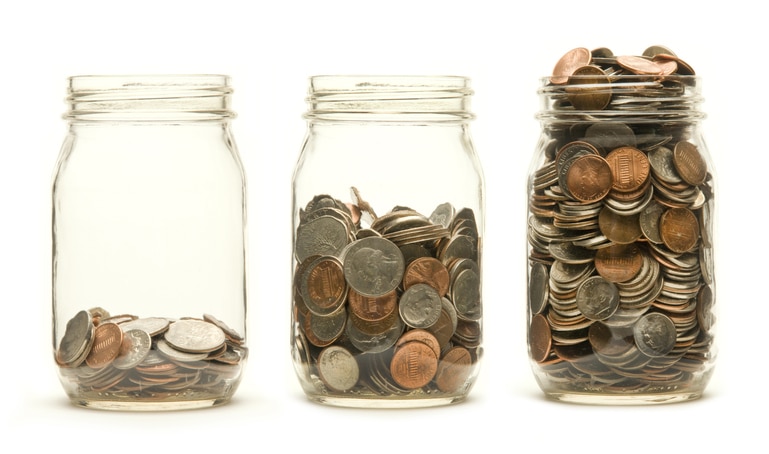 Increasing numbers of American coins in a three glass jars against a white background